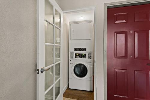 a laundry room with a washing machine and a red door at Red Roof Inn Carson - Wilmington, CA in Wilmington