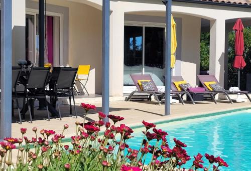 een zwembad met stoelen en bloemen naast een huis bij Villa Jade in Lasserre-de-Prouille