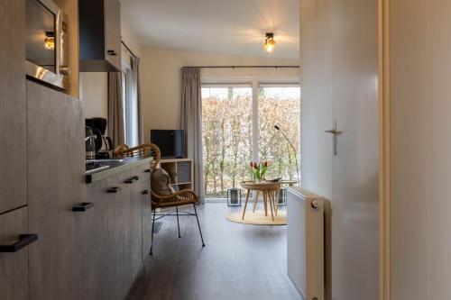 een keuken met een aanrecht, een tafel en een raam bij Gezellig modern chalet midden op de Veluwe in Epe