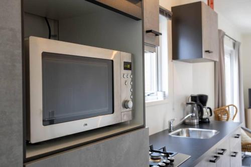 een keuken met een magnetron en een wastafel bij Gezellig modern chalet midden op de Veluwe in Epe