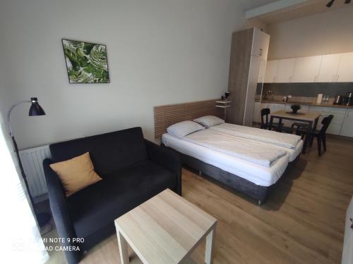 Habitación con cama, sofá y mesa. en Apartamenty na Ceglanej en Oświęcim