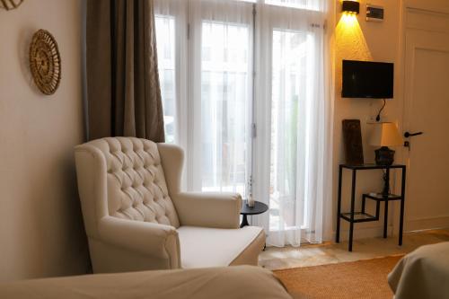 a living room with a white chair and a window at Lilla Maria Guesthouse in Ayvalık