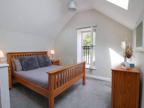 a bedroom with a wooden bed and a window at The Bottling Shed in Matlock