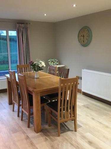 a dining room table with chairs and a clock on the wall at Beech Hill House - Self-Catering in Ballygawley in Ballygawley