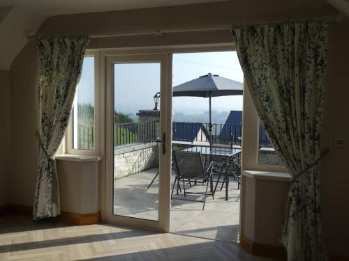 a sliding glass door leading to a patio with an umbrella at Beech Hill House - Self-Catering in Ballygawley in Ballygawley