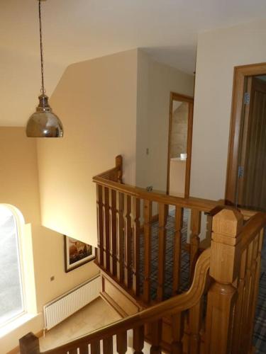 a hallway with a wooden staircase with a pendant light at Beech Hill House - Self-Catering in Ballygawley in Ballygawley