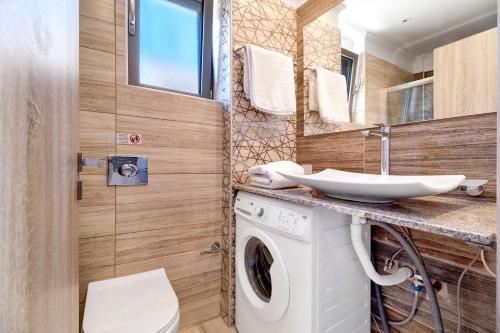uma casa de banho com uma máquina de lavar roupa e um lavatório em Villa Emily em Tsoukaladhes