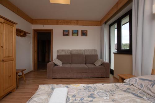 a living room with a couch and a bed at Pod Hawraniem Ski & Bike Friendly in Jurgów