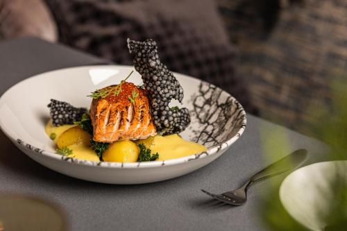 a bowl of food with a fish on a table at Grand Poet Hotel and SPA by Semarah in Riga