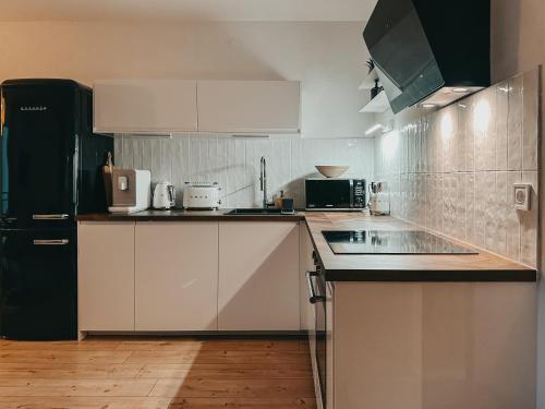 a kitchen with white cabinets and a black refrigerator at House Jelka in Supetar