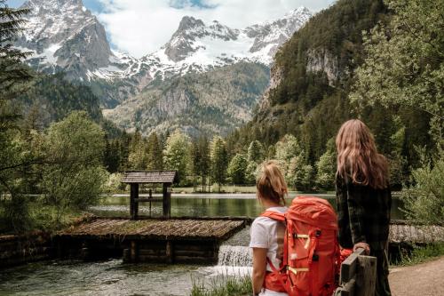 two women with backpacks looking at a mountain lake at Kalkalpen Apartments in Spital am Pyhrn