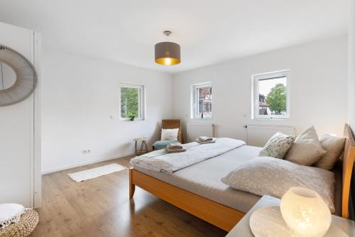 a white bedroom with a large bed and two windows at Ferienwohnung Mittenglück in Unterlenningen