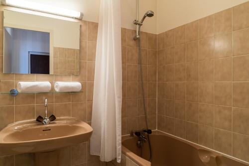 a bathroom with a sink and a mirror and a shower at The Originals Boutique, Hostellerie des Trois Pigeons, Paray-le-Monial (Inter-Hotel) in Paray-le-Monial