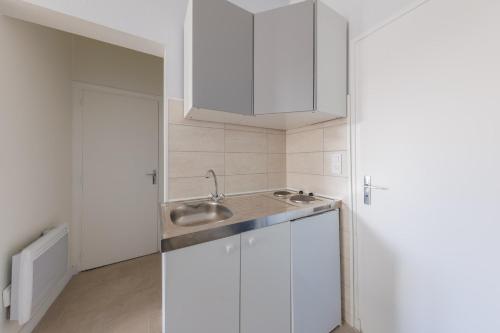 eine Küche mit weißen Schränken und einem Waschbecken in der Unterkunft L'Escale Clermontoise - studio 26m2 in Clermont-Ferrand