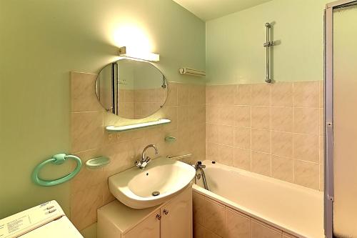 a bathroom with a sink and a mirror and a tub at Les Chênes Rouges - Appt avec piscine partagée in Gérardmer