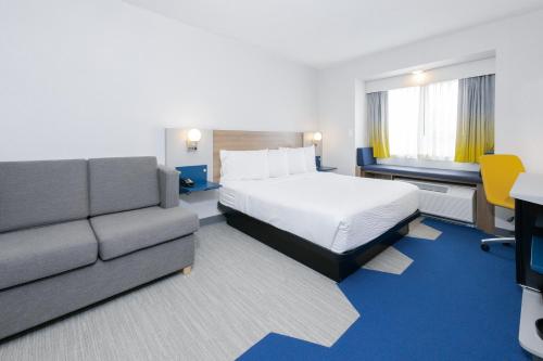 a hotel room with a bed and a couch at Microtel Inn & Suites Springville in Springville
