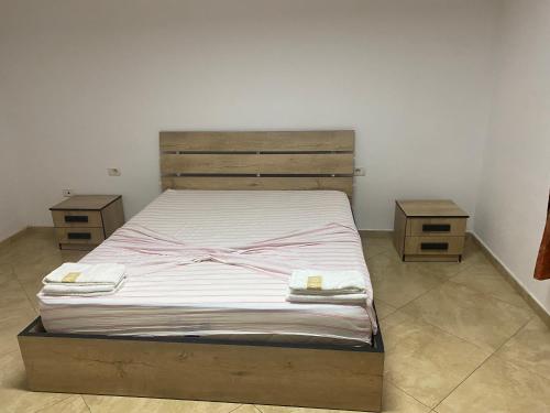 um quarto com uma cama e 2 mesas de cabeceira em madeira em Henri Apartaments em Durrës