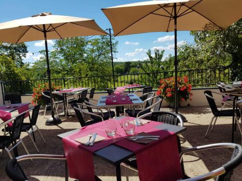 un ensemble de tables et de parasols sur un patio dans l'établissement Auberge d'ici et d'ailleurs, à Cressensac