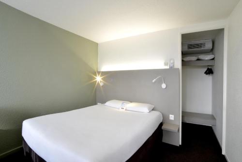 Un dormitorio con una cama blanca con luz. en Kyriad Annecy Nord - Epagny en Metz-Tessy