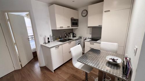une petite cuisine blanche avec une table et des chaises dans l'établissement Charmant apartment in Monmartre, à Paris