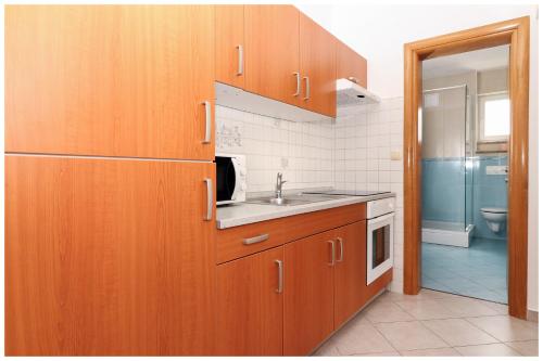una cocina con armarios de madera y fregadero en M&Z Apartmani, en Primošten