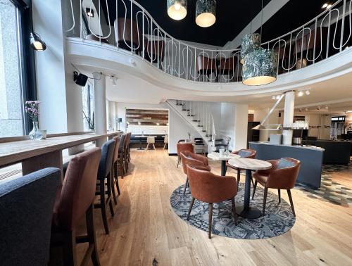 a restaurant with a staircase and tables and chairs at Hotel Berliner Hof by Coffee Fellows Hotels in Kiel