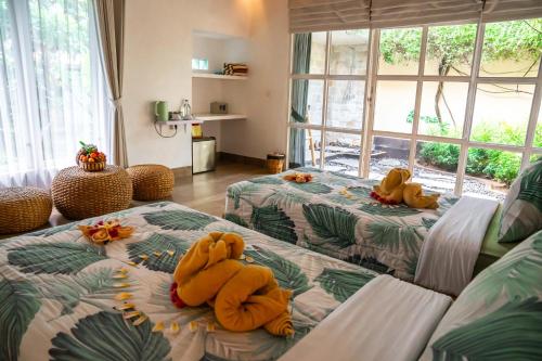 Tulus Hati Ubud Retreat في أوبود: غرفة معيشة بها سريرين عليها حيوانات محشوة