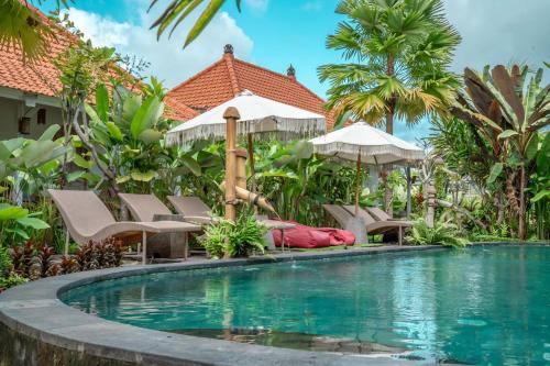 - une piscine dans un complexe avec des chaises et des parasols dans l'établissement Tulus Hati Ubud Retreat, à Ubud