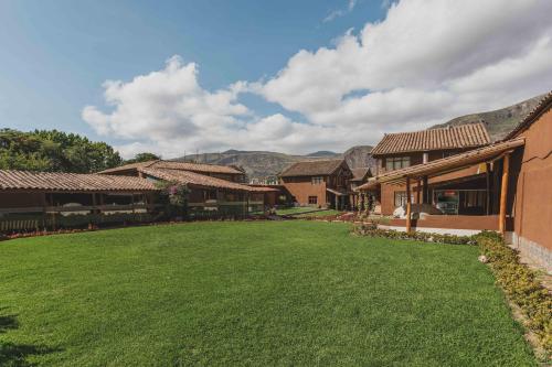 a large yard with houses and mountains in the background at Kutimuy Lodge in Urubamba