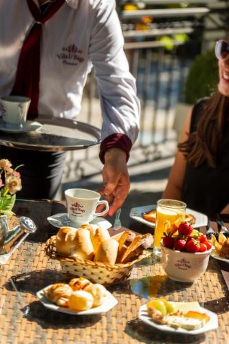 a person is standing at a table with a tray of food at Pousada D'Biagy Premium in Campos do Jordão