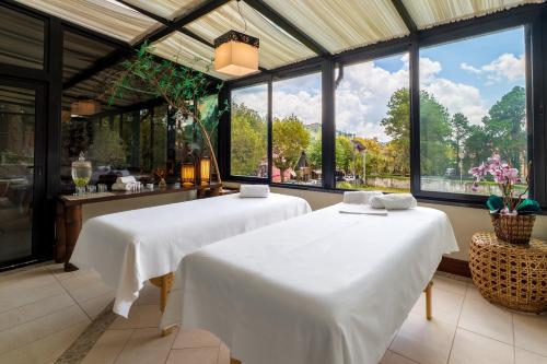 two beds in a room with large windows at Pousada D'Biagy Premium in Campos do Jordão