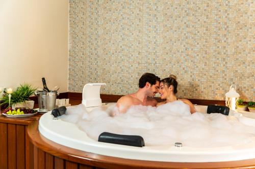 a man and woman sitting in a bath tub at Pousada D'Biagy Premium in Campos do Jordão