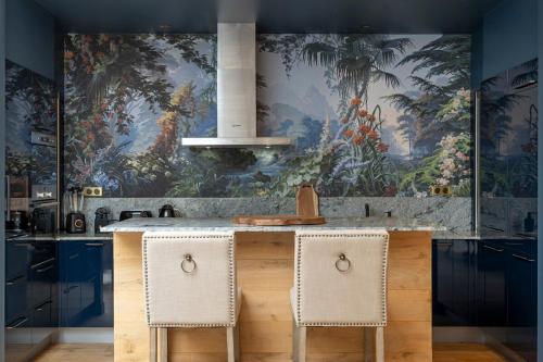 une cuisine avec un îlot avec deux chaises et une fresque murale dans l'établissement La Villa Ballu, à Paris