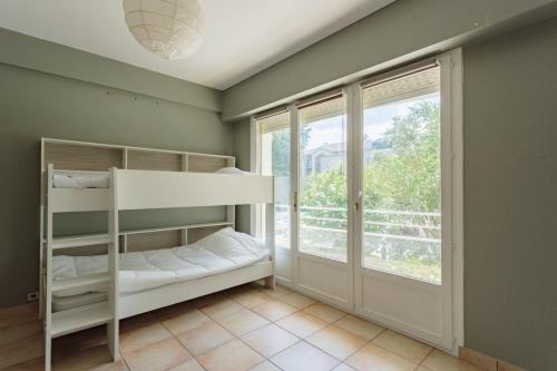 a bedroom with a bunk bed and a window at Appartement d'exception proche des commerces avec piscine in Biarritz