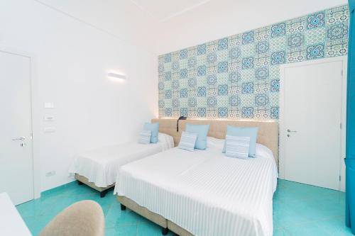 two beds in a room with blue tiles at Hotel Miramare in Maiori