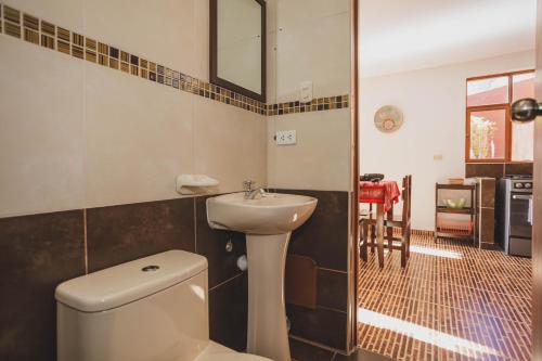 a bathroom with a white toilet and a sink at Kutimuy Lodge in Urubamba