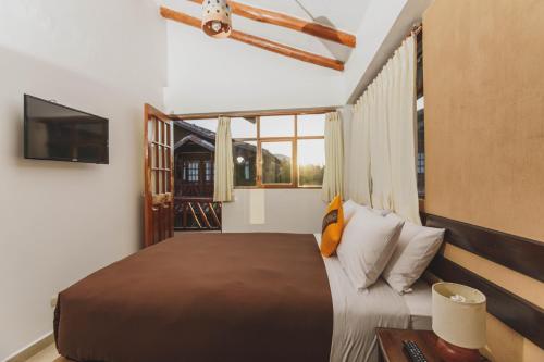 a bedroom with a large bed and a television at Kutimuy Lodge in Urubamba