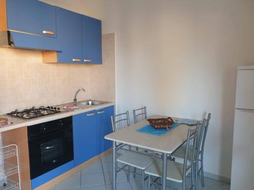 a kitchen with blue cabinets and a table with chairs at Le Residenze di Stintino La Pelosa in Stintino