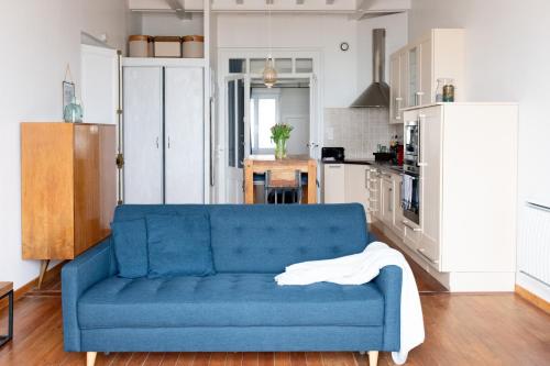 un salon avec un canapé bleu dans une cuisine dans l'établissement La Découverte, appartement front de mer Mers, à Mers-les-Bains