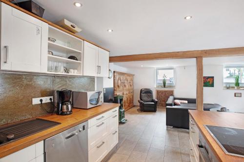 a kitchen with white cabinets and a living room at Ferienwohnung am Marienbach in Kirchhundem