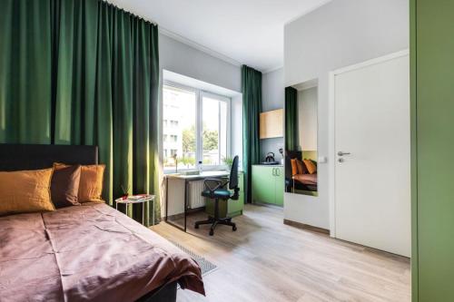 Solo Society Kaunas Apartments في كاوناس: غرفة نوم مع ستائر خضراء ومكتب وسرير