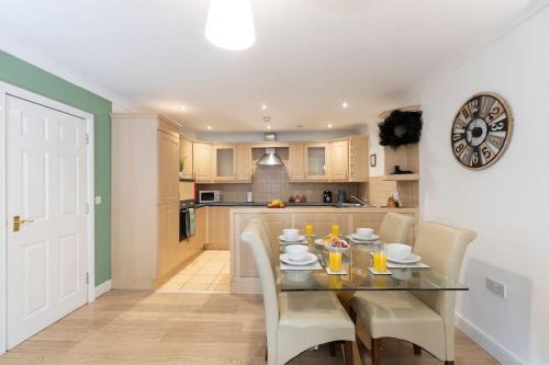 a kitchen with a table and chairs and a clock on the wall at Albert Park View (free parking!) in Middlesbrough