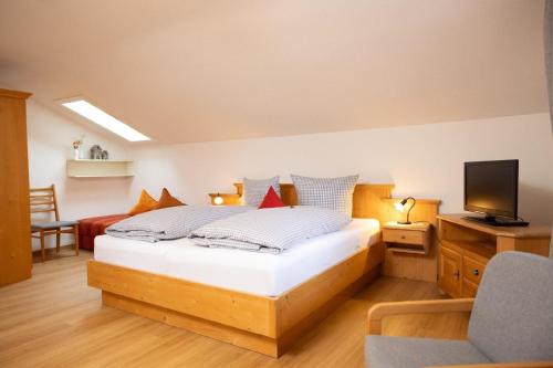een slaapkamer met een bed, een televisie en een stoel bij Ferienwohnung Rosenwirth - b45171 in Mittenwald