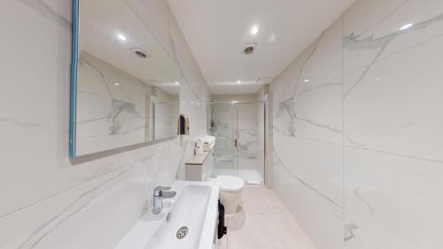 a white bathroom with two sinks and a toilet at MSK Hotel 82 in London
