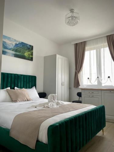 a bedroom with a large bed with a green headboard at Casa Bursucilor in Moşniţa Nouă