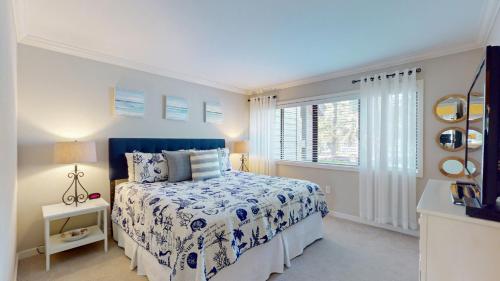 a bedroom with a bed with a blue bedspread and a window at 284 Turnberry Village in Hilton Head Island