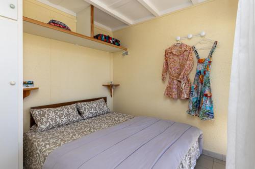 ein Schlafzimmer mit einem Bett und einem an der Wand hängenden Kleid in der Unterkunft Chalet cosy - vacances en famille in Léon