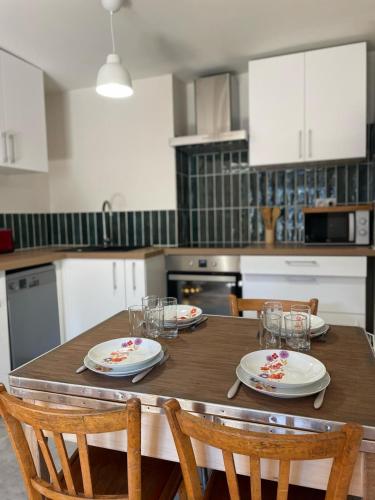 une cuisine avec une table en bois, des assiettes et des chaises dans l'établissement Les appartements d'Albertine - Clémence, à Bourges