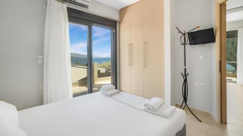 a bedroom with a white bed and a large window at Agni Suites in Nikiana