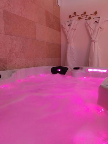 une salle de bain avec des lumières roses dans une baignoire dans l'établissement L instant Chaumois - Moment zen aux Sables d Olonne, à Les Sables-dʼOlonne